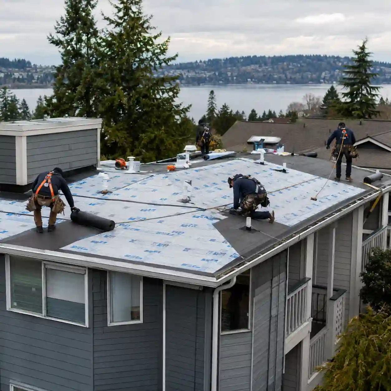 Renton Roofing crew installing underlayment on a multi-unit roof overlooking the lake